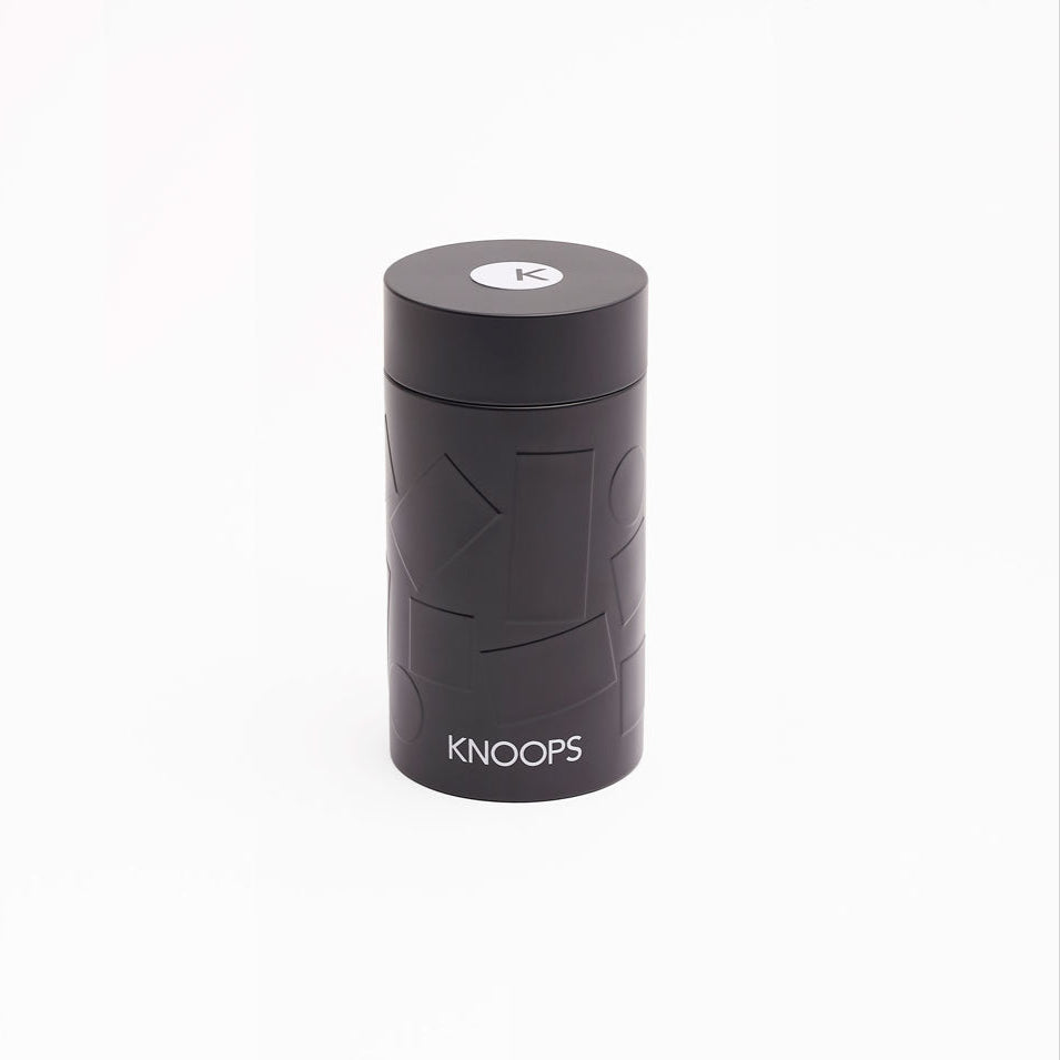 A black cylindrical tin with the brand name 'KNOOPS' written on it.