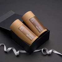 Two KooPs coffee containers in a black box with a silver ribbon on a dark background